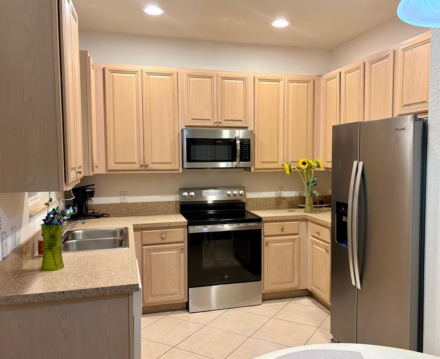 A kitchen with light wood cabinets, stainless steel appliances, and speckled tan countertops — 188 W Thatch Palm Circle, Jupiter FL 33458, JUPITER, FL