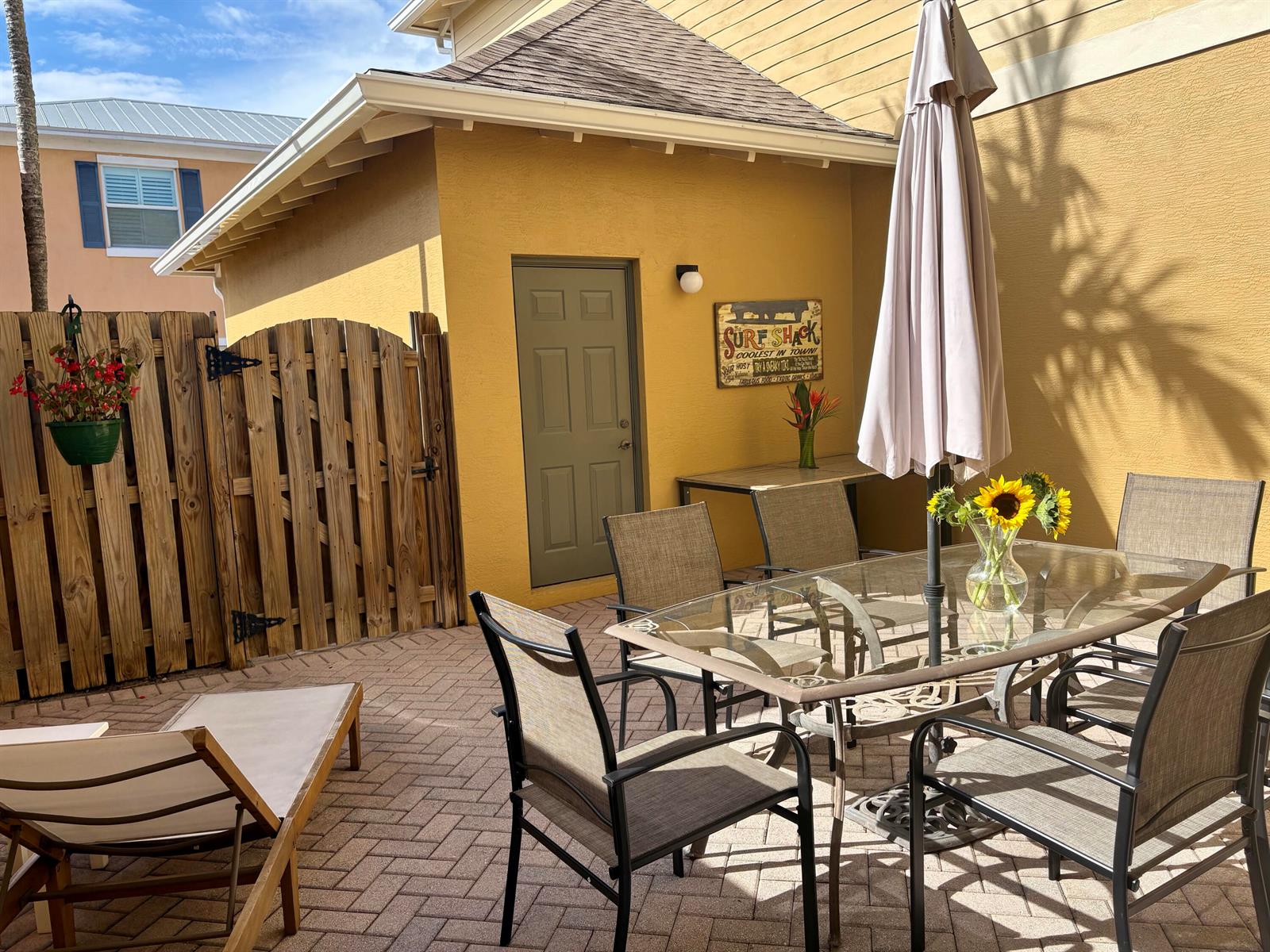 A patio features a glass-top dining table, chairs, a lounge chair, and a wooden fence — 188 W Thatch Palm Circle, Jupiter FL 33458, JUPITER, FL