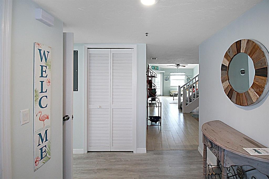 An entryway features a welcome sign, a louvered closet door, and a wooden console table — 1206 SIESTA BAYSIDE DRIVE UNIT 1206B, SARASOTA, FL