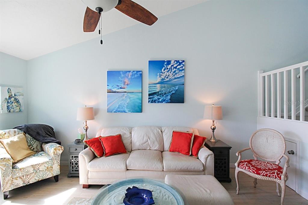 A living room features a white sofa, two armchairs, and beach-themed wall art — 1206 SIESTA BAYSIDE DRIVE UNIT 1206B, SARASOTA, FL