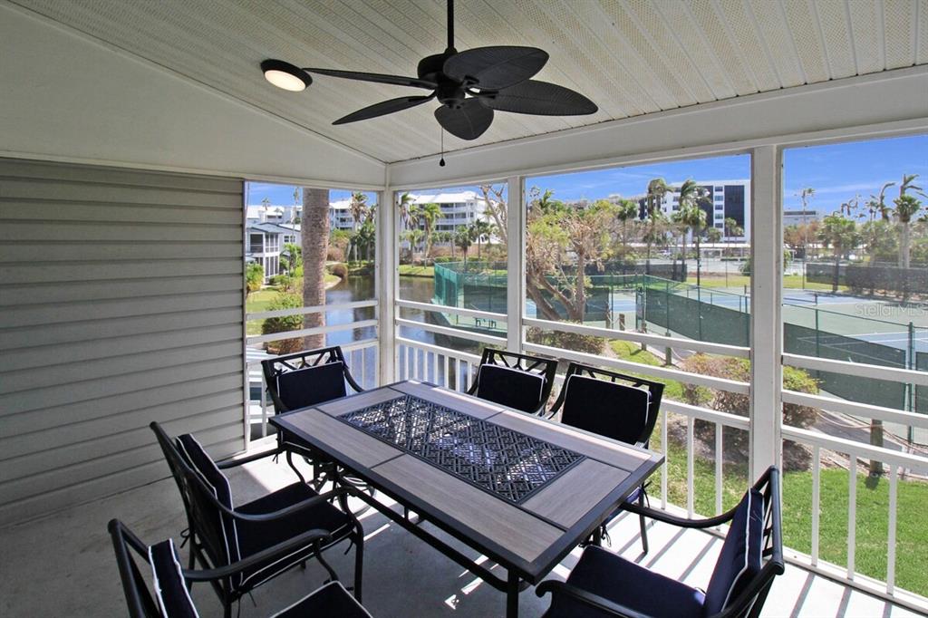 A screened-in porch features a dining set, a ceiling fan, and views of tennis courts — 1206 SIESTA BAYSIDE DRIVE UNIT 1206B, SARASOTA, FL
