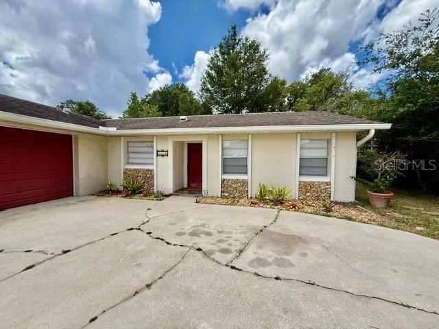 A single-story house features a red garage door, a central entrance, and a cracked driveway — 1114 S PEARL STREET, DELAND, FL