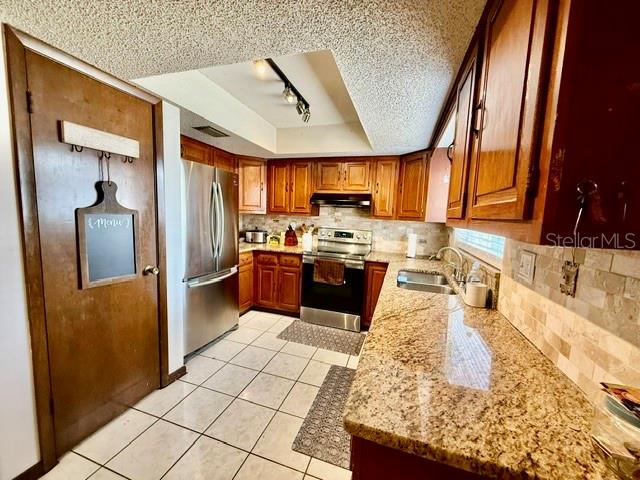 A kitchen features wood cabinets, granite countertops, stainless steel appliances, and a tiled backsplash — 1114 S PEARL STREET, DELAND, FL