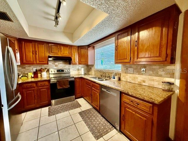 A kitchen features wood cabinets, granite countertops, stainless steel appliances, and tiled flooring — 1114 S PEARL STREET, DELAND, FL
