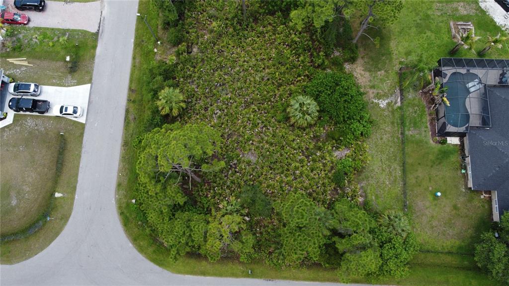 An aerial view shows a vacant, wooded residential lot situated between a road and a house — RING STREET, NORTH PORT, FL