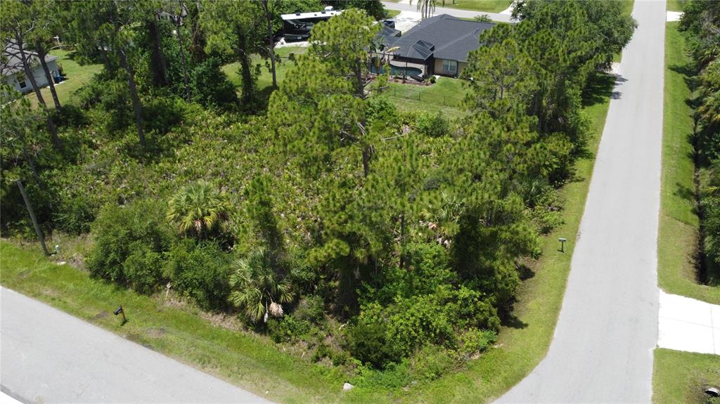 An aerial view shows a vacant, wooded corner lot surrounded by paved roads and houses — RING STREET, NORTH PORT, FL