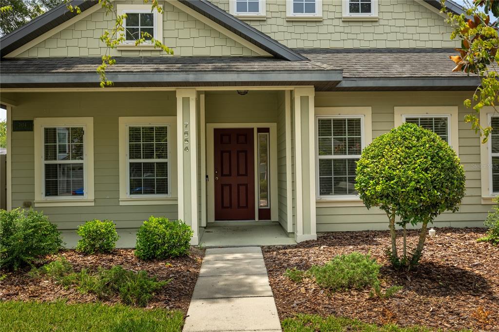The exterior of a light green house features a red front door and a walkway — 7654 SW 79TH DRIVE, GAINESVILLE, FL