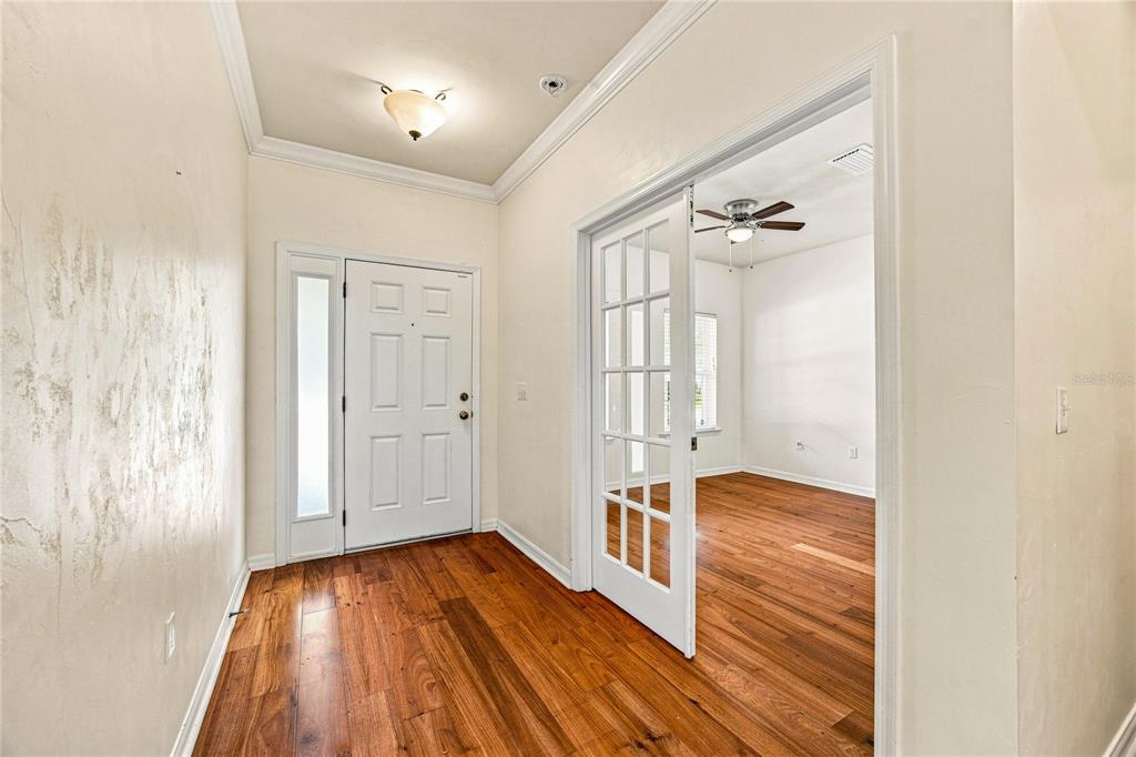 A foyer with wood flooring leads to a white front door and a glass-paneled door — 7654 SW 79TH DRIVE, GAINESVILLE, FL