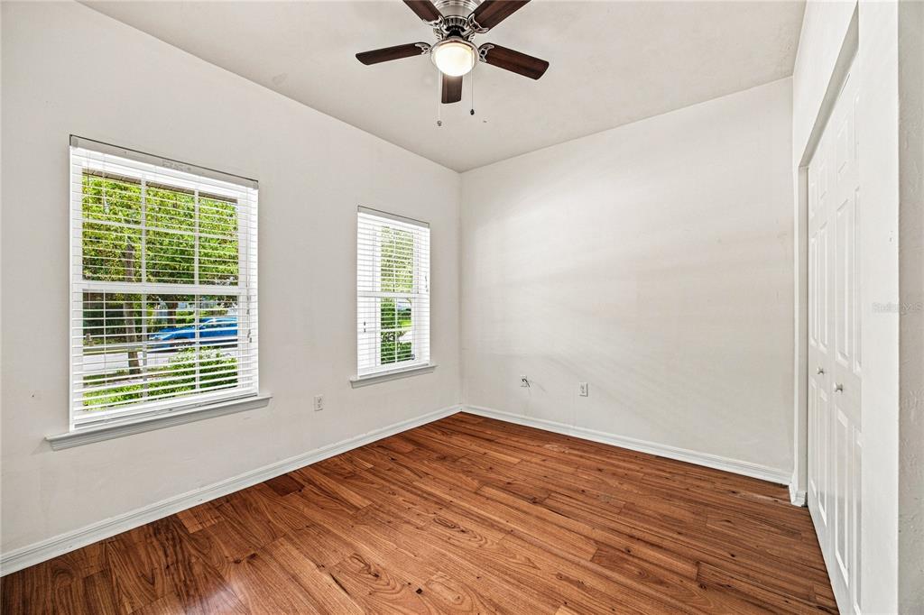 An empty room with wood-look flooring, white walls, two windows with blinds, and a ceiling fan — 7654 SW 79TH DRIVE, GAINESVILLE, FL