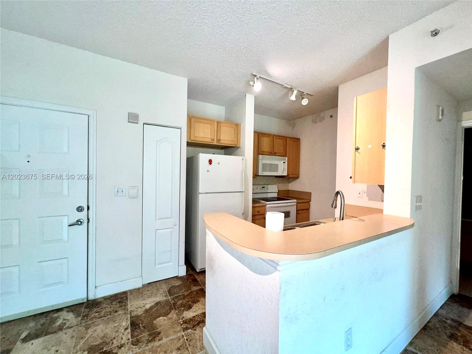 A kitchen features light wood cabinets, white appliances, a breakfast bar, and tiled flooring — 6001 SW 70th St # 454, South Miami FL 33143, SOUTH MIAMI, FL