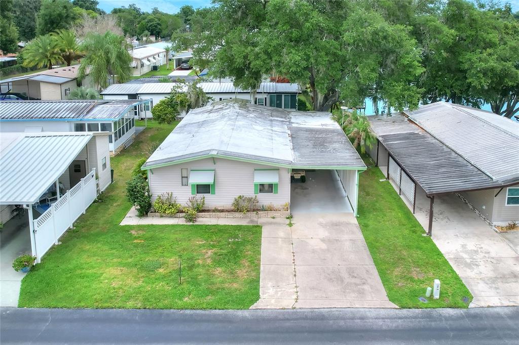 An aerial view of a single-story mobile home with a carport and a grassy lawn — 2055 S FLORAL AVENUE UNIT 296, BARTOW, FL