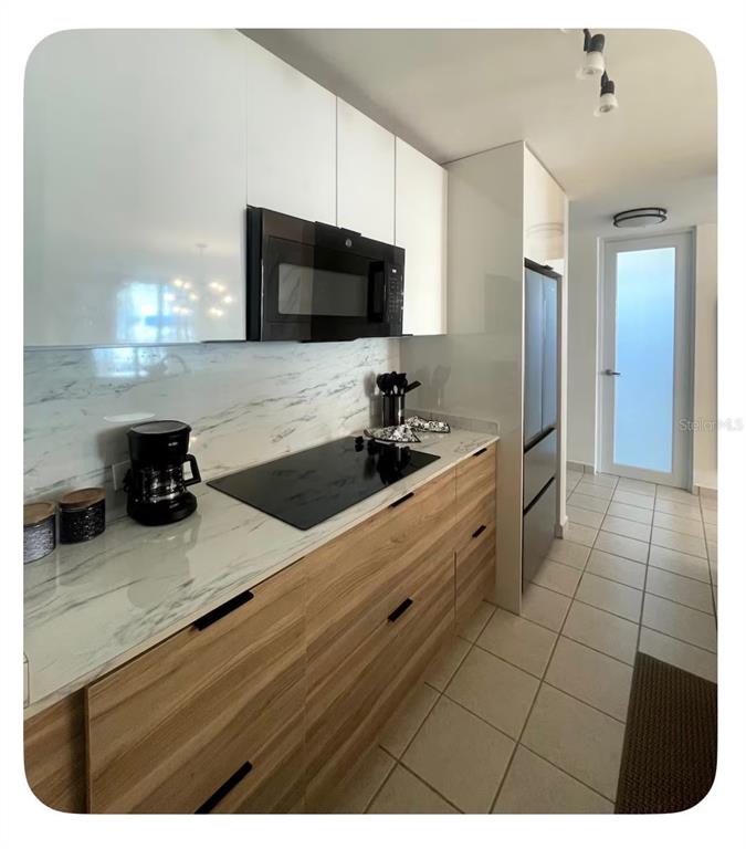 A modern kitchen features wood-grain lower cabinets, white upper cabinets, and a marble-patterned countertop — 306 OCEAN WALK CHALETS, LUQUILLO, PR