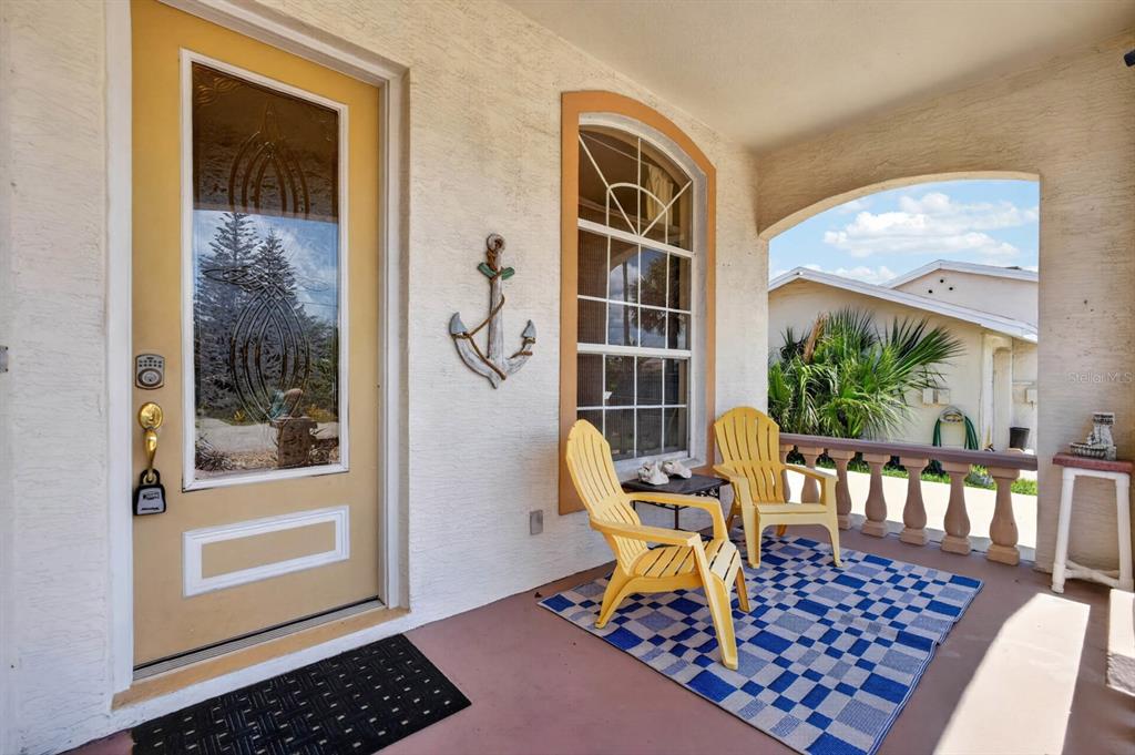 A covered front porch features a yellow door, two yellow chairs, and a blue rug — 497 GRANDVIEW AVENUE, ORMOND BEACH, FL