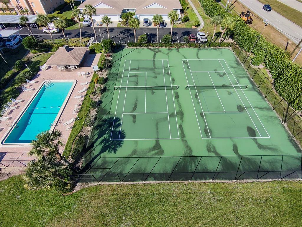 An aerial view shows two tennis courts next to a swimming pool and patio area — 9610 VICTORIA LANE UNIT D202, NAPLES, FL