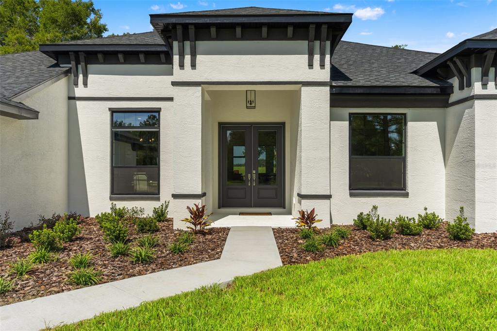 The exterior of a white stucco house features a dark double-door entrance and black trim — 10264 S LECANTO HIGHWAY, LECANTO, FL