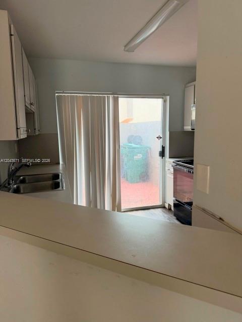 A kitchen features white cabinets, a stainless steel sink, and a sliding glass door — 6256 SW 129th Ave, Miami FL 33183, MIAMI, FL
