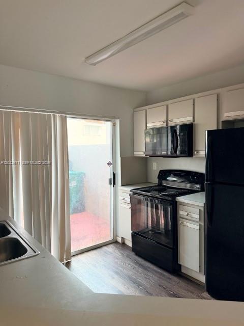 A kitchen features white cabinets, black appliances, and a sliding glass door to a patio — 6256 SW 129th Ave, Miami FL 33183, MIAMI, FL