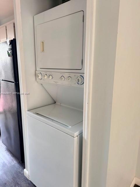 A white stacked washer and dryer unit sits in a narrow closet next to a refrigerator — 6256 SW 129th Ave, Miami FL 33183, MIAMI, FL
