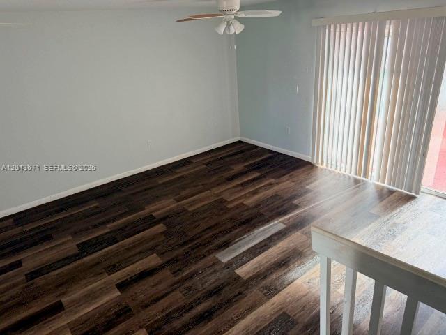 An empty room features dark wood-look flooring, light blue walls, and vertical window blinds — 6256 SW 129th Ave, Miami FL 33183, MIAMI, FL