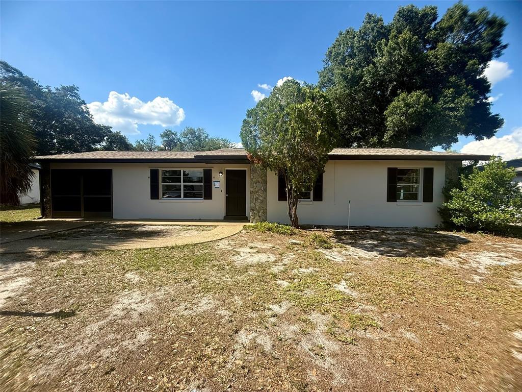 A single-story house with a light-colored exterior, dark shutters, and a front-facing tree — 131 SPARROW AVENUE, SEBRING, FL