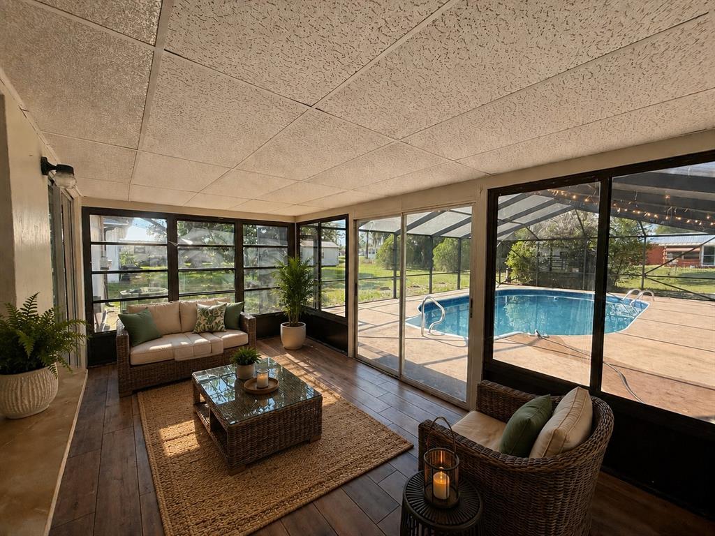 A sunroom with tile flooring, wicker furniture, and a view of an outdoor swimming pool — 131 SPARROW AVENUE, SEBRING, FL