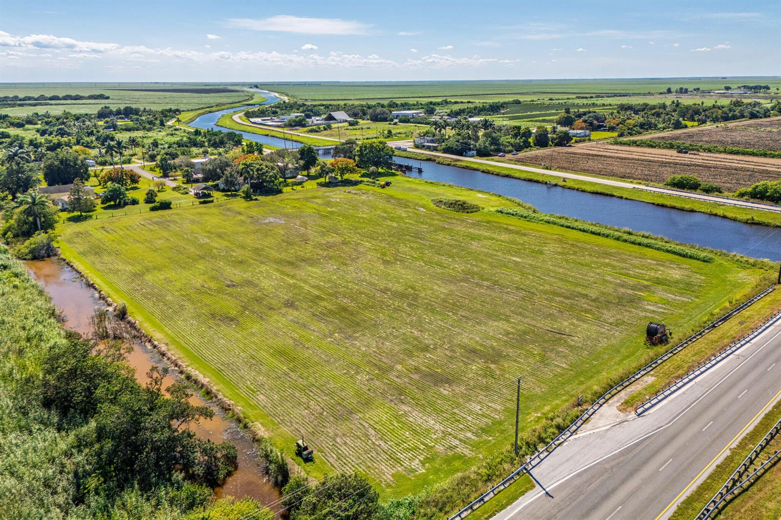 An aerial view shows a large, grassy field bordered by a canal and a highway — 0 Us-27, Clewiston FL 33440, CLEWISTON, FL