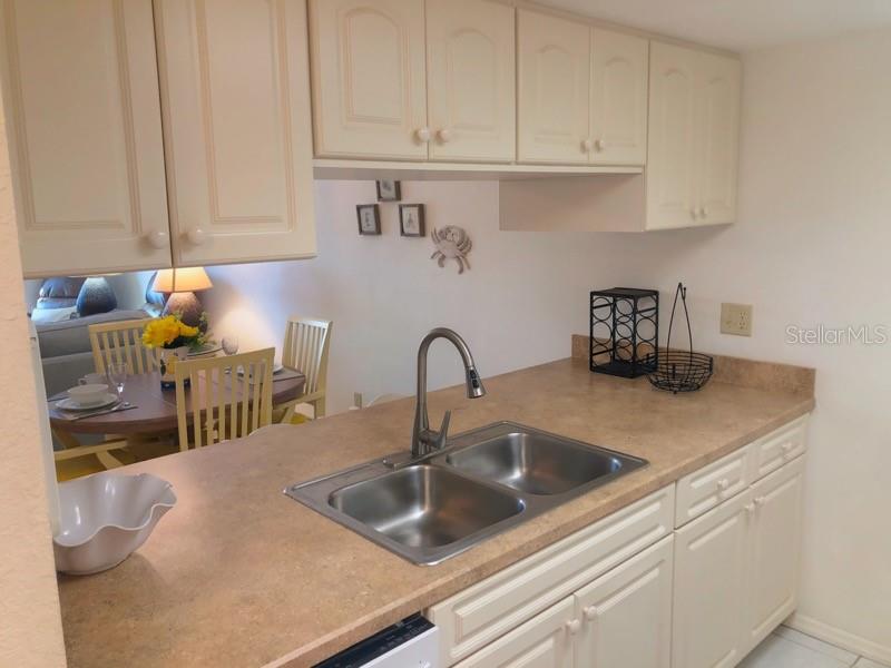 A kitchen with light-colored cabinets, a double-basin sink, and a view into the dining area — 4024 OAKVIEW DRIVE UNIT I3, PUNTA GORDA, FL
