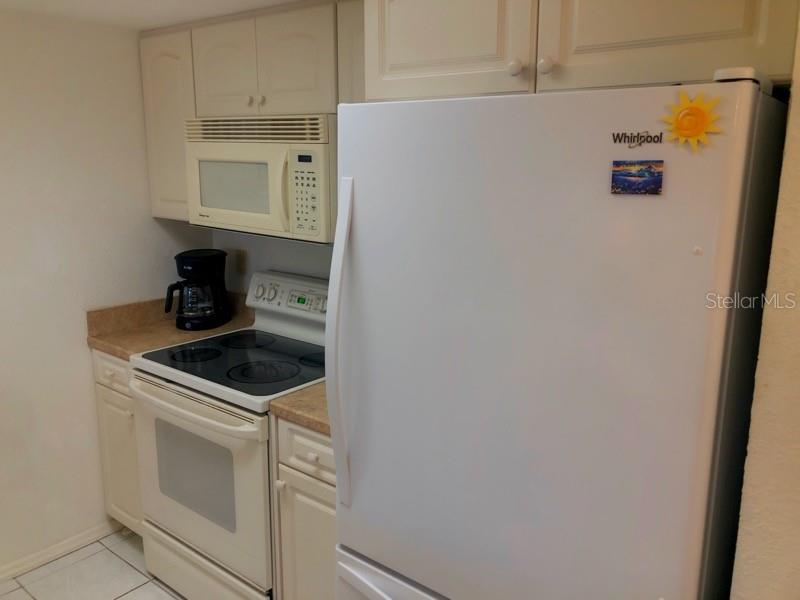 A kitchen features white cabinets, a white refrigerator, a white stove, and a microwave — 4024 OAKVIEW DRIVE UNIT I3, PUNTA GORDA, FL