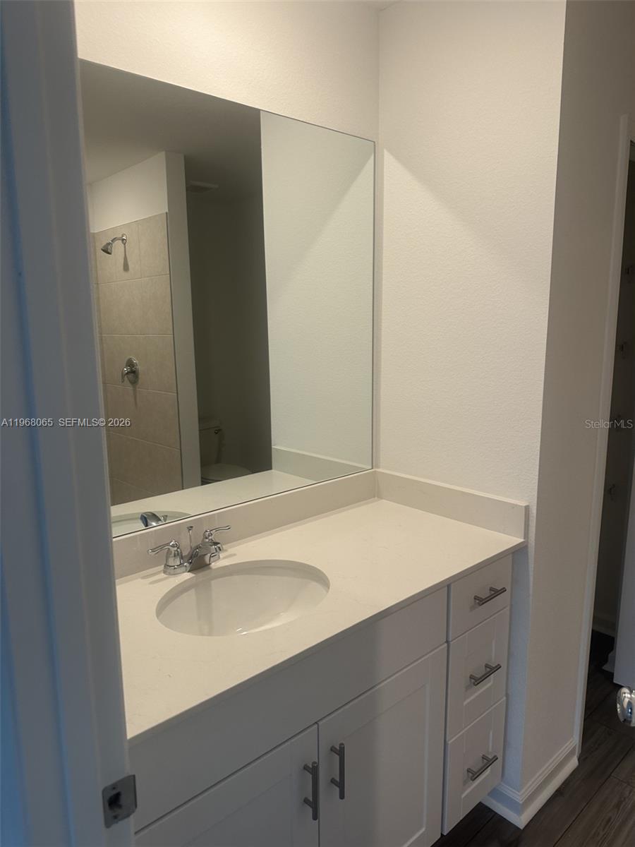 A bathroom features a white vanity with a quartz countertop, a sink, and a mirror — 8934 SW 135TH ST, Ocala FL 34473, OCALA, FL