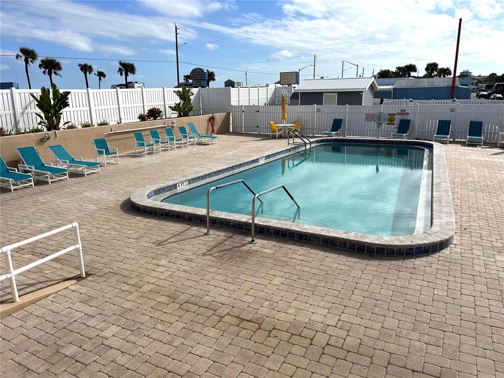 An outdoor swimming pool is surrounded by a paved deck with lounge chairs and fencing — 169 LOOKOUT DRIVE, FLAGLER BEACH, FL