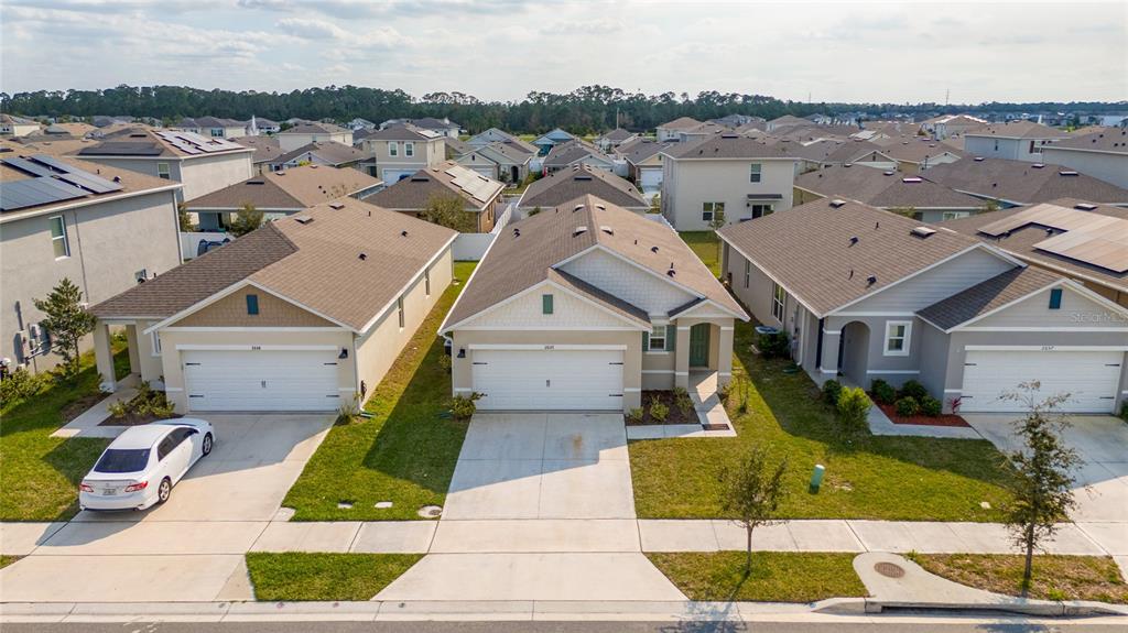 An aerial view shows three suburban houses with driveways and lawns on a sunny day — 2653 HARMONIA HAMMOCK ROAD, HARMONY, FL