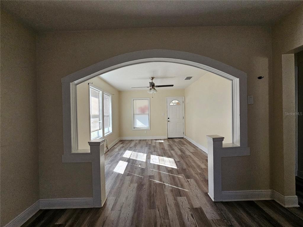A room with wood-look flooring viewed through a large arched opening with two half-walls — 701 N 7TH ST, HAINES CITY, FL