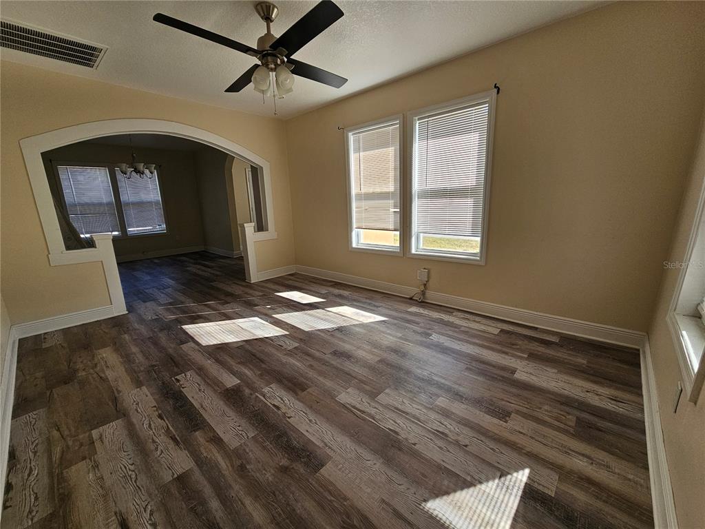 An empty room with wood-look flooring, a ceiling fan, and an arched entryway — 701 N 7TH ST, HAINES CITY, FL