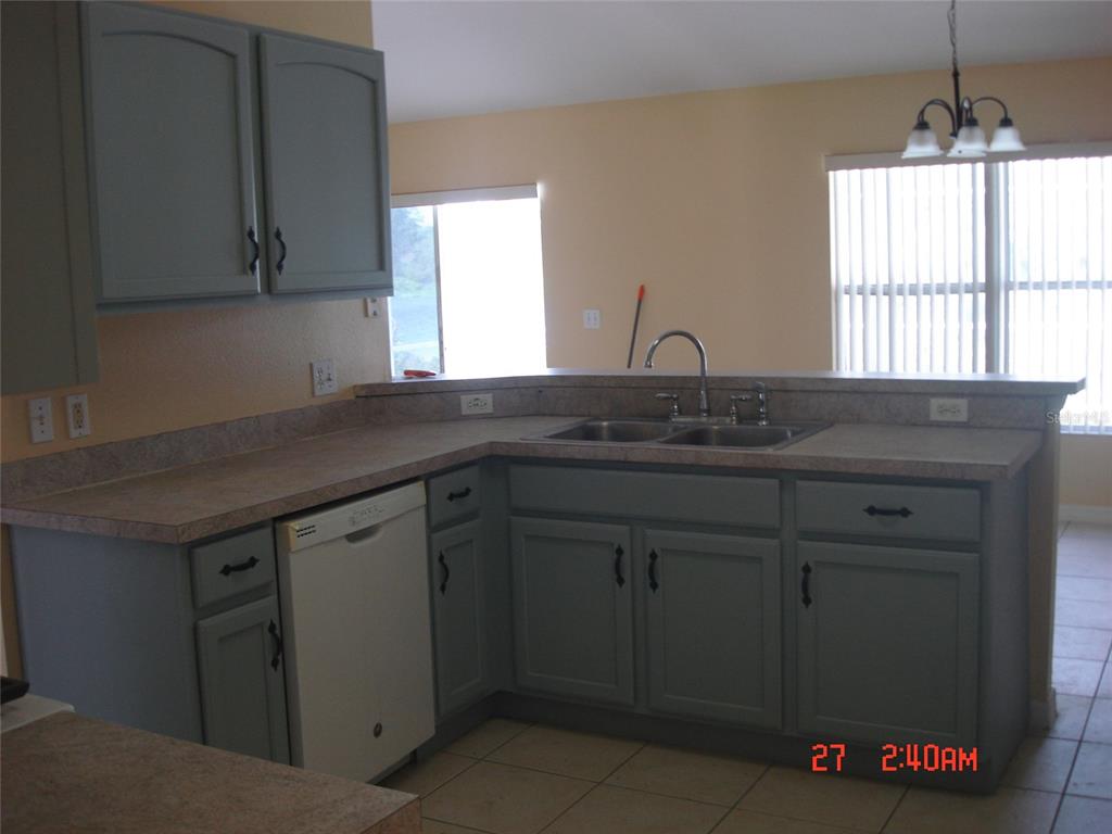 A kitchen features gray cabinets, laminate countertops, a double sink, and a white dishwasher — 606 ALDER GROVE DRIVE, DELTONA, FL