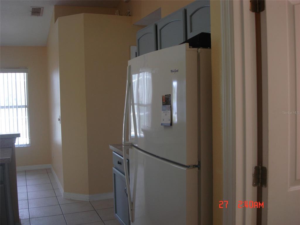 A white refrigerator stands in a kitchen with light-colored walls and tiled flooring — 606 ALDER GROVE DRIVE, DELTONA, FL