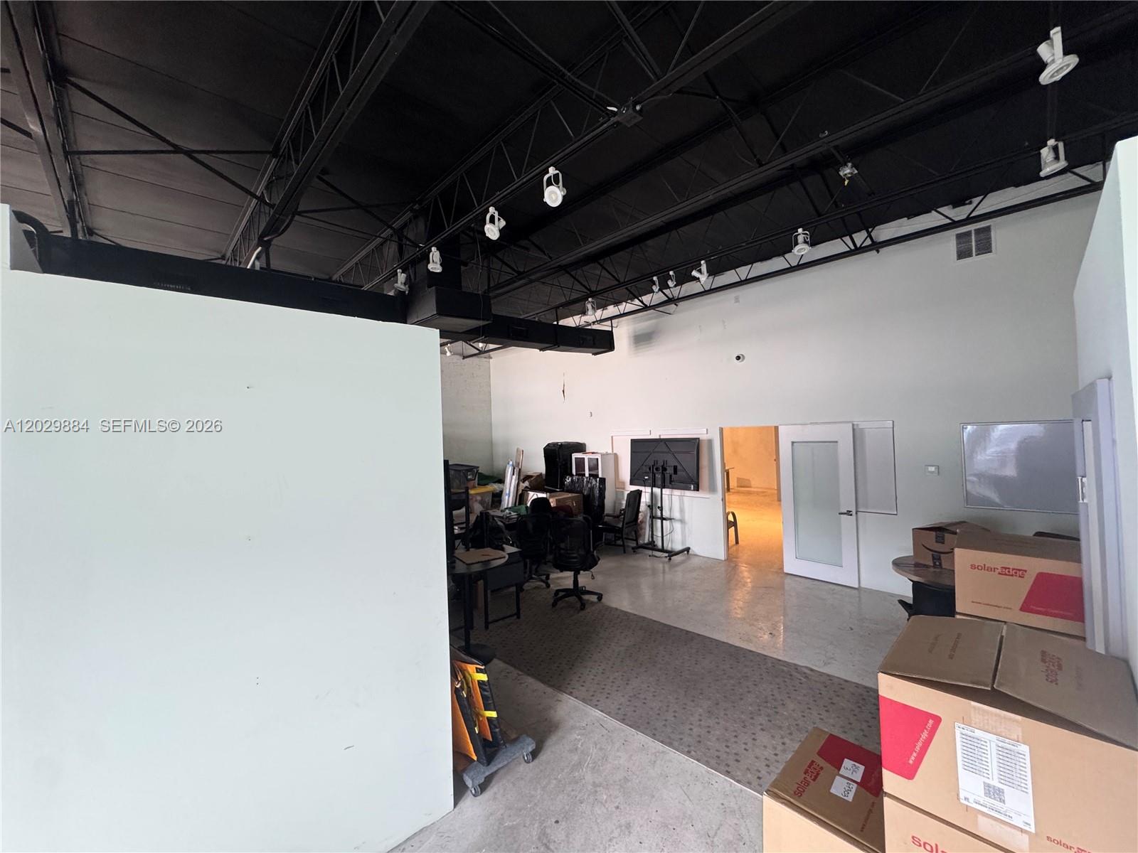 An interior view of a commercial office space with exposed ceiling trusses and concrete floors — 3241 NW 38th St, Miami FL 33142, MIAMI, FL