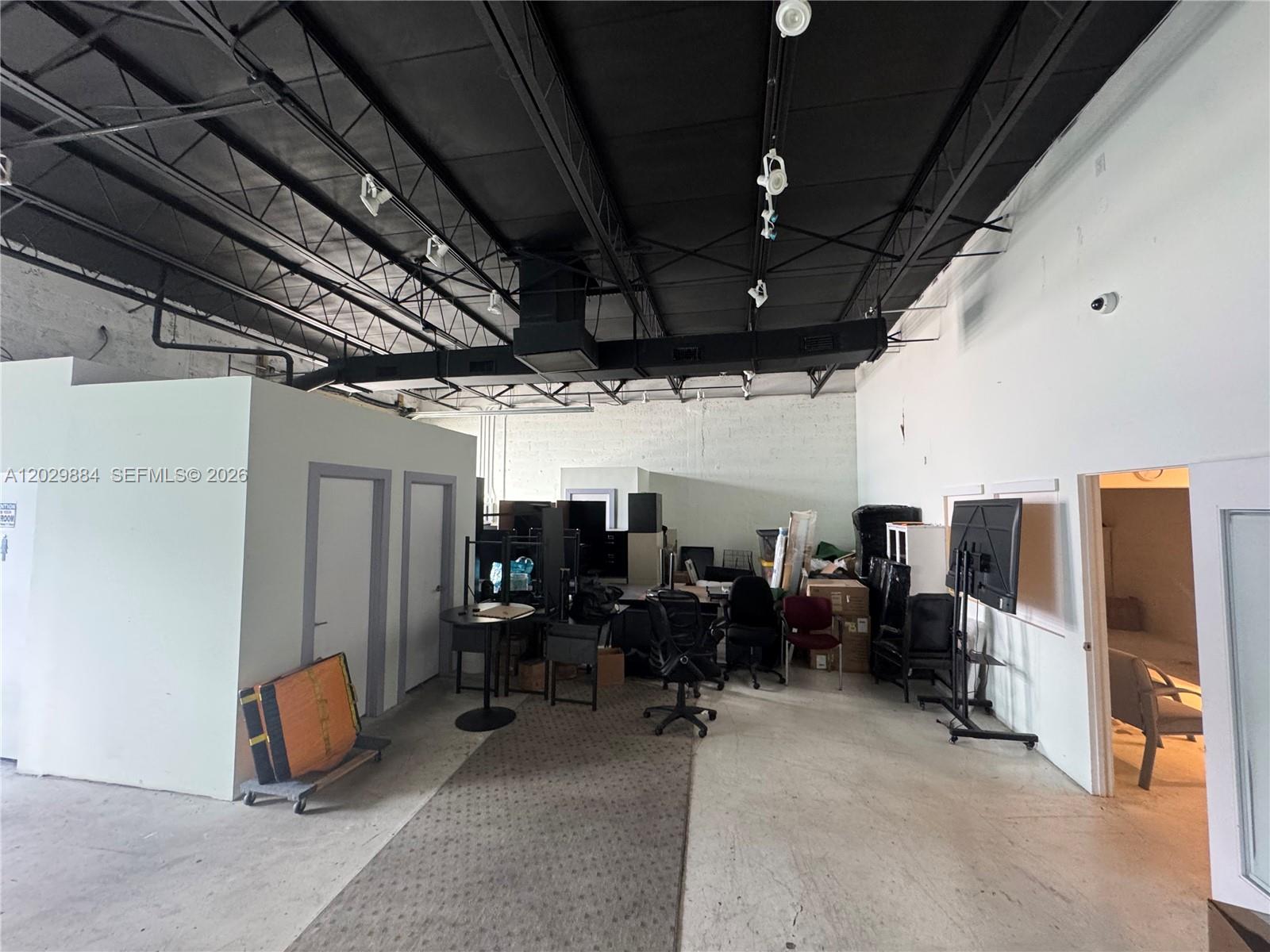 An industrial-style office space features an exposed black ceiling, concrete floors, and partitioned rooms — 3241 NW 38th St, Miami FL 33142, MIAMI, FL