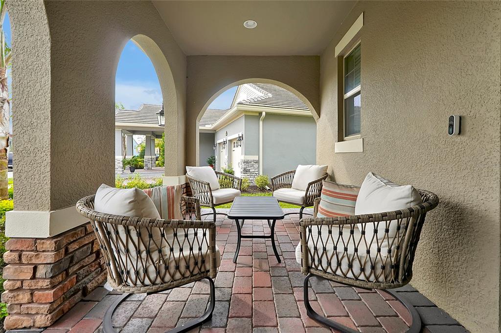 A covered patio features four wicker chairs, a small table, and brick pavers — 9827 BEACH PORT DRIVE, WINTER GARDEN, FL