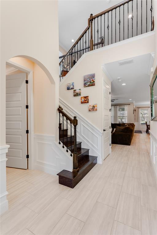 A foyer features a wooden staircase with iron railings, light tile flooring, and arched doorways — 9827 BEACH PORT DRIVE, WINTER GARDEN, FL