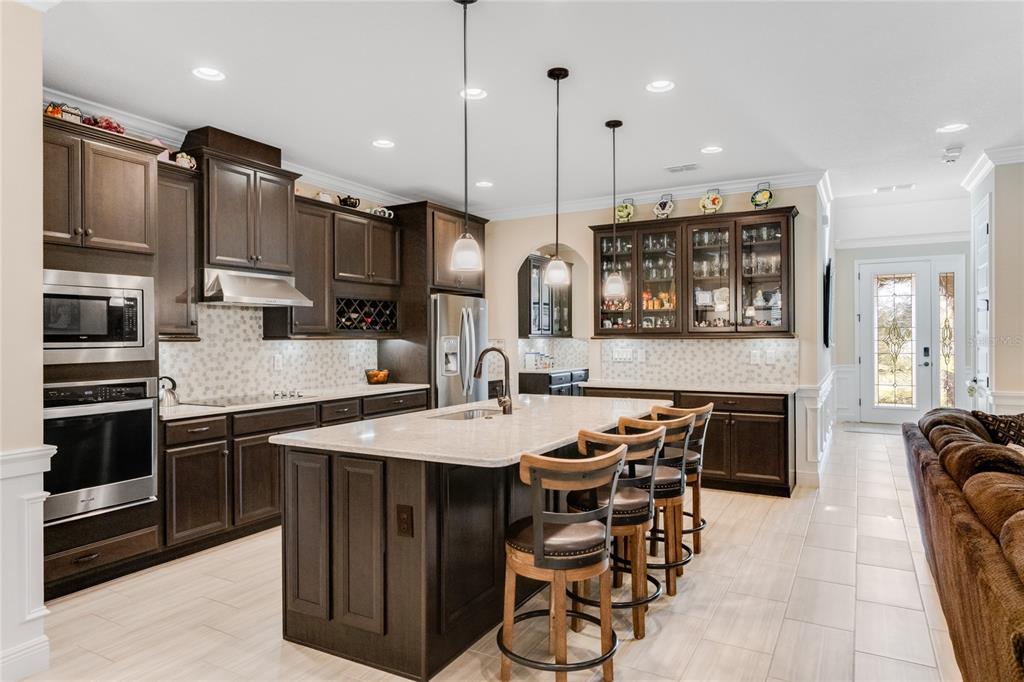 A kitchen features dark wood cabinetry, a large island with bar seating, and light countertops — 9827 BEACH PORT DRIVE, WINTER GARDEN, FL