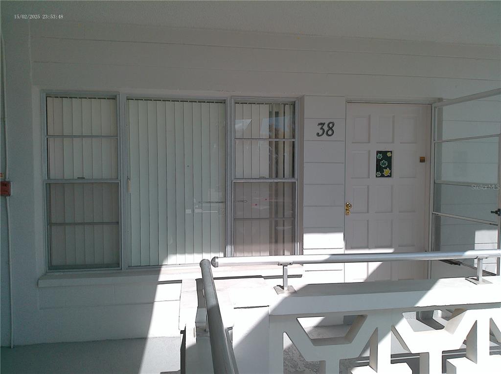 The exterior entrance of a residential unit features a white door numbered 38 and windows — 2456 ECUADORIAN WAY UNIT 38, CLEARWATER, FL