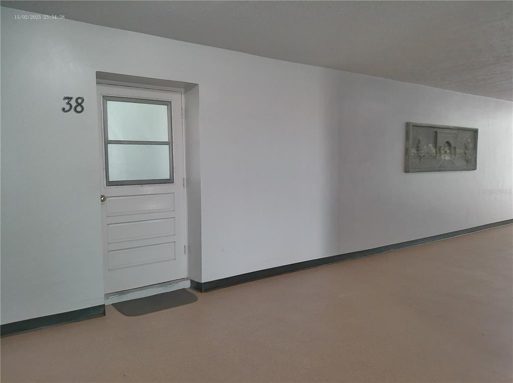 A white door labeled 38 is set into a plain wall along a hallway — 2456 ECUADORIAN WAY UNIT 38, CLEARWATER, FL