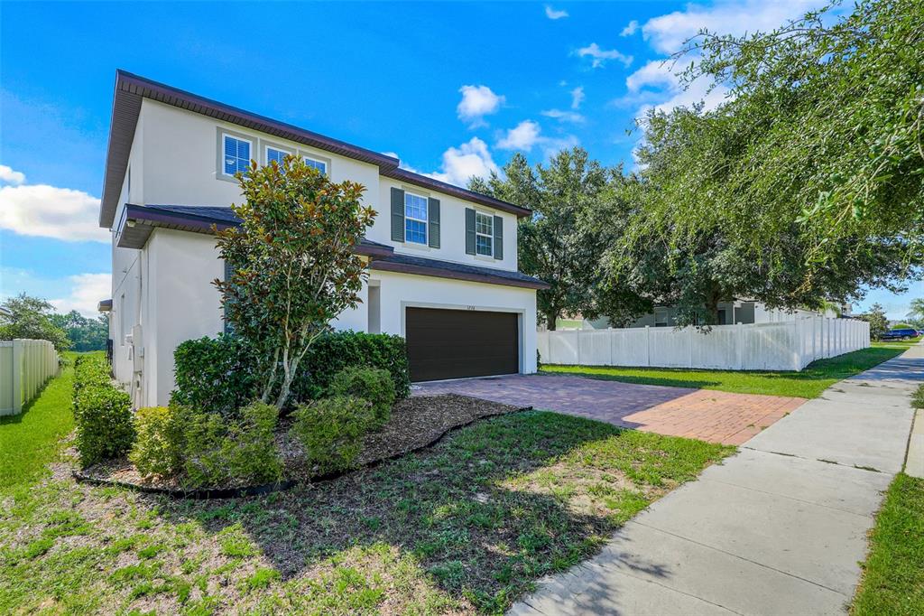 A two-story house with a brown garage door, white stucco walls, and a paved driveway — 1230 STRATTON AVENUE, GROVELAND, FL