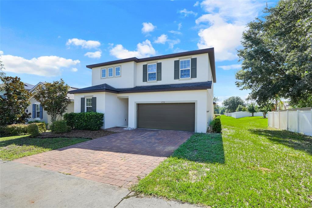 A two-story house with a beige stucco exterior, a brown garage door, and a brick driveway — 1230 STRATTON AVENUE, GROVELAND, FL