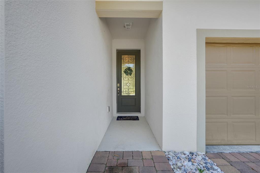 A recessed entryway features a dark front door with decorative glass and a garage door — 1230 STRATTON AVENUE, GROVELAND, FL