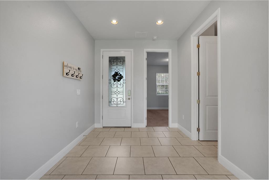 A tiled entryway features a white front door with decorative glass and two interior doorways — 1230 STRATTON AVENUE, GROVELAND, FL