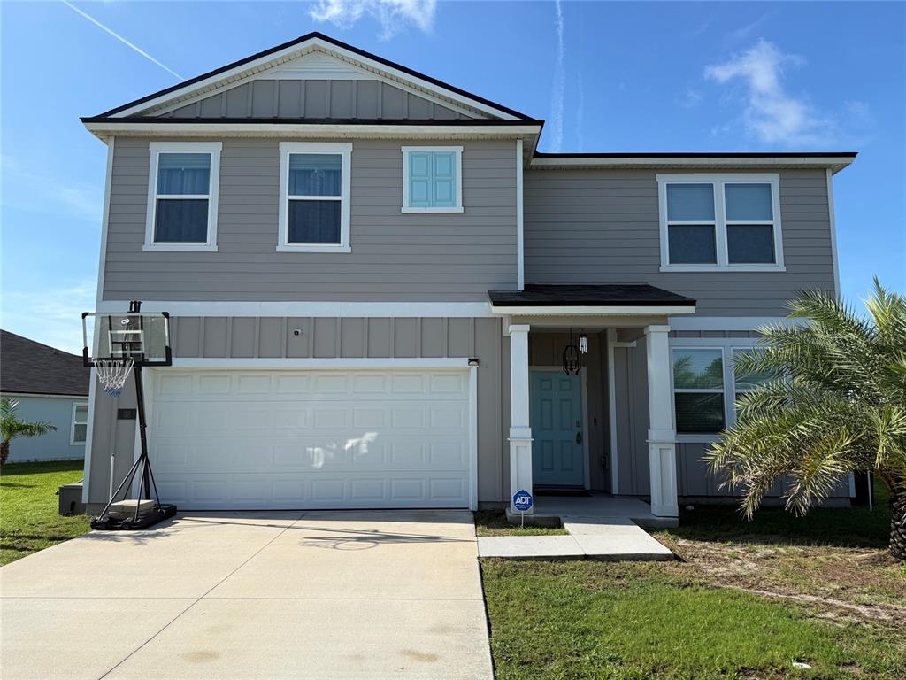 A two-story house with light gray siding, a white garage door, and a front porch — 38 HULETT WOODS ROAD, PALM COAST, FL