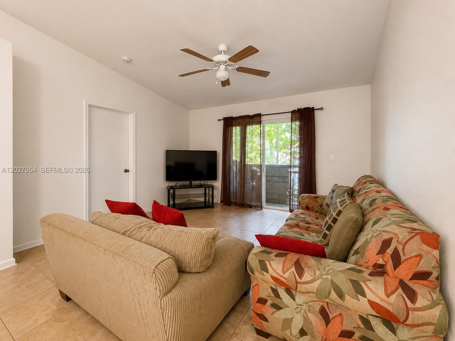 A living room features a patterned sofa, a beige loveseat, a television, and a sliding door — 3680 NW 91st Ln # 3680, Sunrise FL 33351, SUNRISE, FL