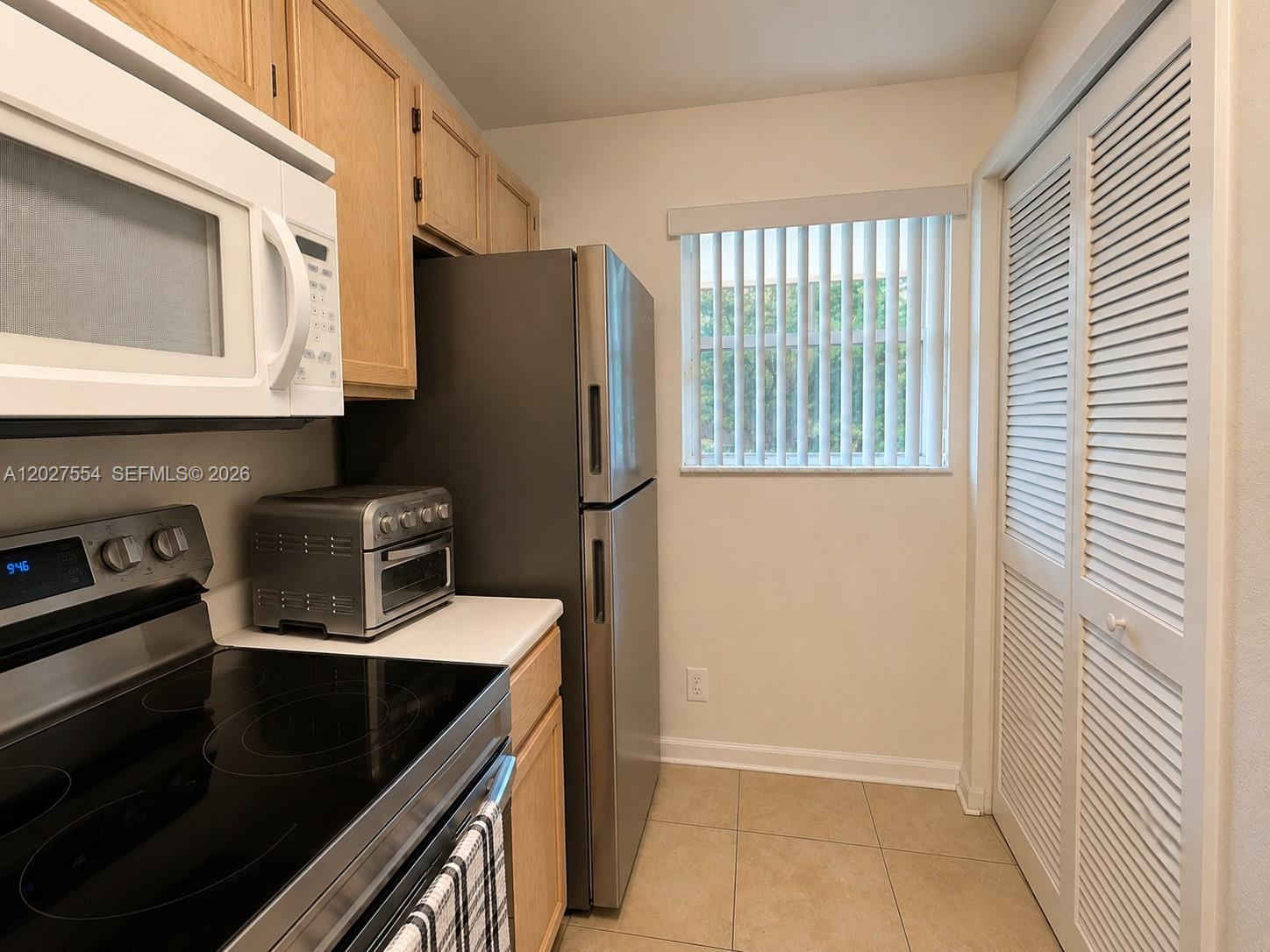 A kitchen features light wood cabinets, stainless steel appliances, and a window with vertical blinds — 3680 NW 91st Ln # 3680, Sunrise FL 33351, SUNRISE, FL
