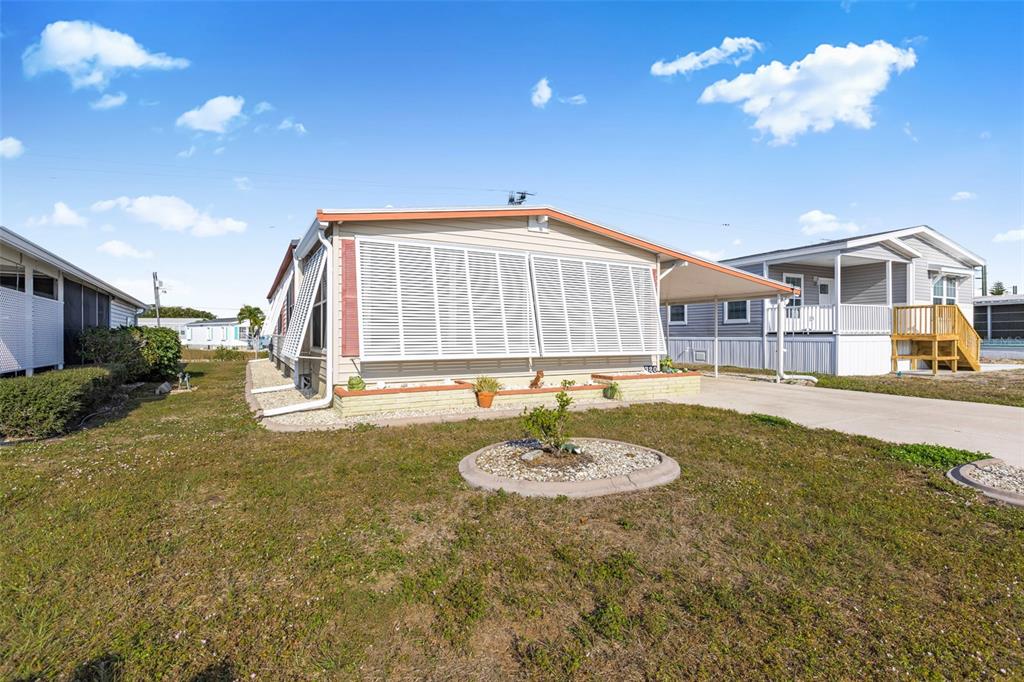 A single-story manufactured home with white siding, louvered shutters, and a concrete driveway — 320 LA COSTA, NORTH PORT, FL